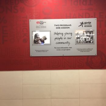Wendy's - a red wall with a sign that says two people are helping young people in community - Fast Food Near Me - Hammond, Indiana
