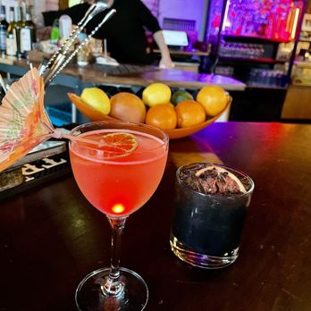 Dimestore Delibar - a glass of cocktail with an umbrella on the bar - New American Near Me - Denver, Colorado