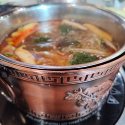 Szechuan Beef Tallow broth with pork belly, rice cakes, broccoli, bean sprouts, and shiitake mushrooms.
