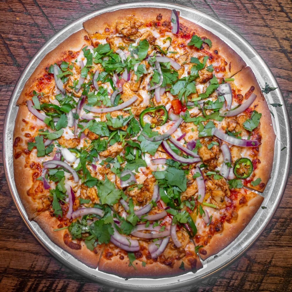 Pizza Vibes - a pizza on a pan on a wooden table - Pizza Near Me - The Colony, Texas