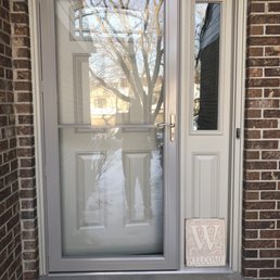 Front door - A white front door with a large glass panel and a narrow side window, set in a brick exterior wall, with a welcome sign at the bottom.