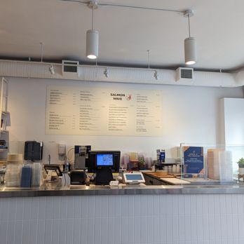 Salmon Wave - a restaurant counter with menus on the wall - Sushi Bars Near Me - Burnaby, British Columbia