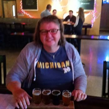 Jolly Pumpkin Artisan Ales - a woman sitting at a table with a tray of beer - Breweries Near Me - Dexter, Michigan