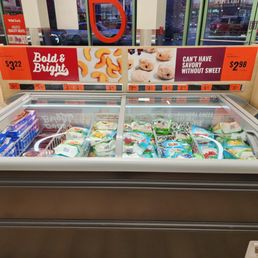 Frozen dairy items are stored in a glass-top freezer at Wild Fork, with price tags and promotional signage visible above.