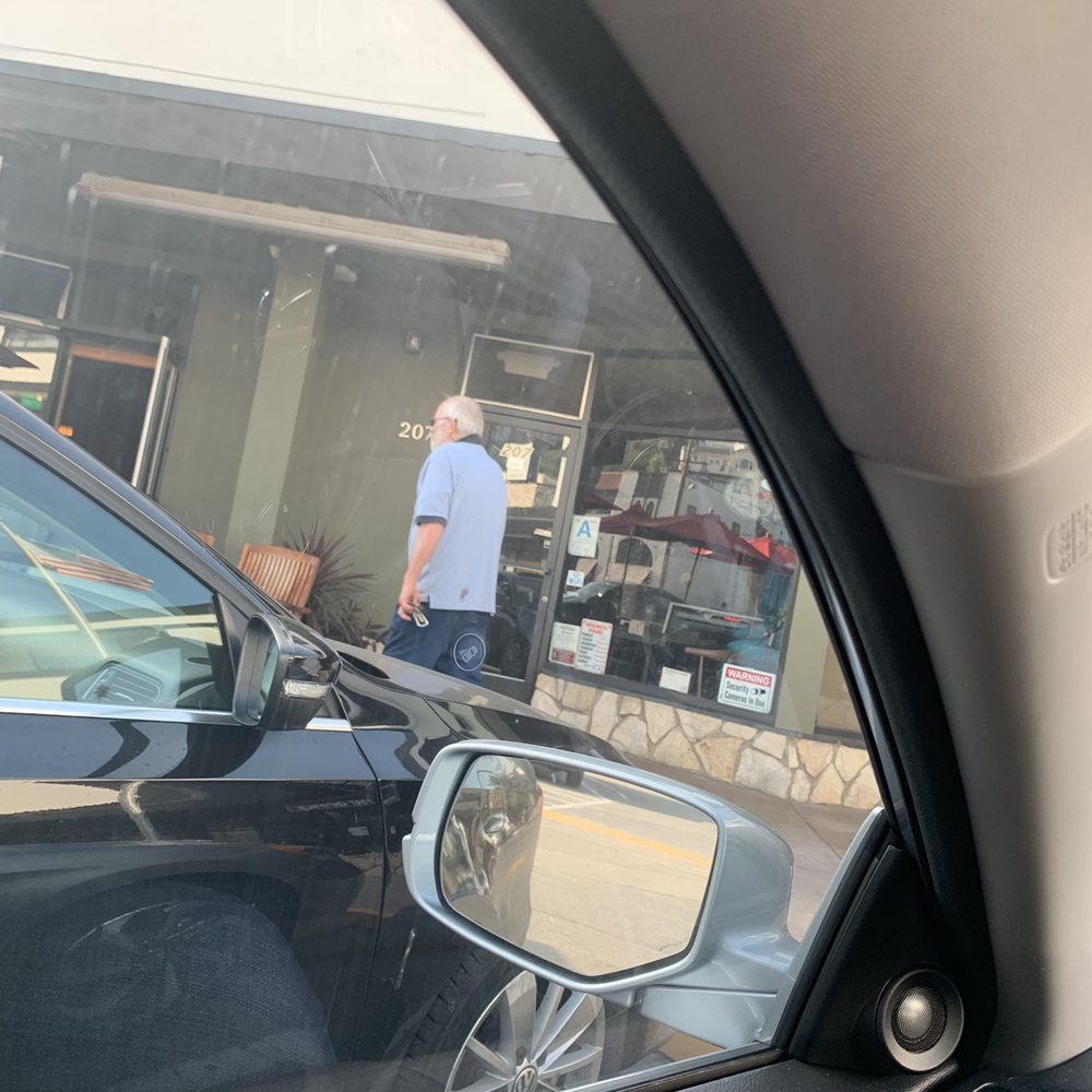 The postmaster shuffling around the parking lot while customers wait in front of a locked post office, during regular business hours.