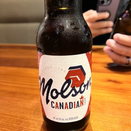 a man taking a picture of a bottle of beer
