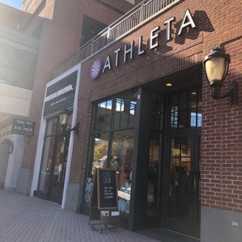 Athleta - Athleta retail store exterior with a brick facade, large glass windows, and a sign displaying the store name. A sidewalk and a chalkboard sign are visible outside. - Sports Wear Near Me - Richmond, Virginia