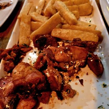 Boteco Do Manolo - frango a passarinho (fried chicken crispy yet NOT breaded) and yuca fries, partially attacked prior to pic - A rectangular plate contains fried chicken pieces, yuca fries, and fried plantains, served in a restaurant setting. - Brazilian Near Me - Framingham, Massachusetts