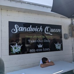 a man sleeping on a table in front of a sandwich queen sign