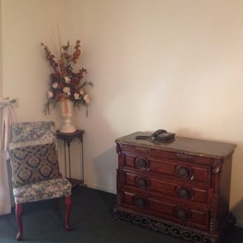Firebaugh Riverfront Inn - Chair, dried floral arrangement & small dresser in room. - Hotels Near Me - Firebaugh, California