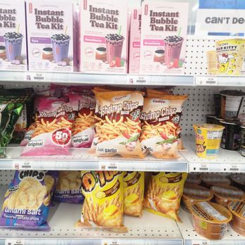 Five Below - International snacks - The image shows store shelves stocked with snack foods and beverages, including instant bubble tea kits in purple and pink boxes, shrimp chips in pink and green packaging, flavored potato chips in purple and yellow bags, and various yogurt and pudding cups. The products are arranged in multiple rows with price tags visible beneath each item, indicating a retail environment focused on snack and convenience foods. - Discount Store Near Me - Richmond, Virginia