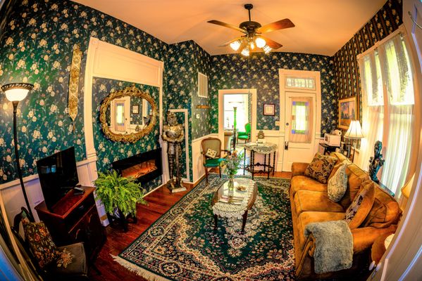 Tennyson Suite | King - King Jacuzzi suite, in a lovely Victorian home, with full size living room, covered front porch over downtown, and an extra private shower nestled in the cliffs on your back deck.

In the 1892 Victorian building that was the home of Eureka Springs first Mayor
Full size living room with original wood floors and molding
The couch pulls out to a comfortable queen size bed. ($25 extra person fee, for 3rd breakfast, linens, etc.)
King bed
Private two-person outdoor shower with built in Bluetooth speaker and dual shower-head
Two-person Jacuzzi and waterfall shower inside
First floor, with four steps from the garden to your front porch