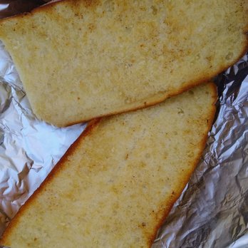 The Spaghetti Shack - Garlic bread - Two slices of garlic bread with a golden-brown crust are placed on crumpled aluminum foil. - Italian Near Me - Tempe, Arizona