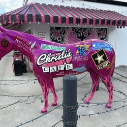 Christi's Cafe - A hot pink horse statue in outside with advertisements and military support.