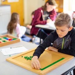 Greensboro Montessori School - A 4th grader uses a tactile learning material to help him find the square root, the lowest common multiple, and factors of a number.