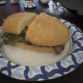 Earl's BBQ - Rib-Eye Steak Sandwich - A sandwich with bread, lettuce, and meat is placed on a decorative paper plate with a blue and white pattern. - Donuts Near Me - Chicago, Illinois