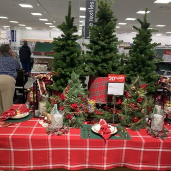 Boscov's - The image shows a Christmas display at Boscov in Rochester, NY, with three decorated evergreen trees and a table covered with a red plaid tablecloth. The table is set with holiday-themed decorations, including plates, napkins, and ornaments, and a sign indicating a 20% discount. The background reveals store aisles and shoppers, indicating a retail environment during the holiday season. - Department Stores Near Me - Rochester, New York
