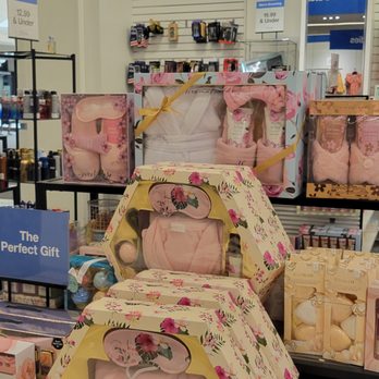 Macy's Backstage - Gift sets - The image shows a retail display of beauty gift sets on a store shelf, with packaging decorated with floral designs. The gift sets include items such as bath products and accessories, arranged in hexagonal boxes and other packaging. In the background, there is a blue sign labeled 'Beauty' and shelves with additional products, indicating a section dedicated to beauty and personal care items. - Women's Clothing Near Me - Montebello, California