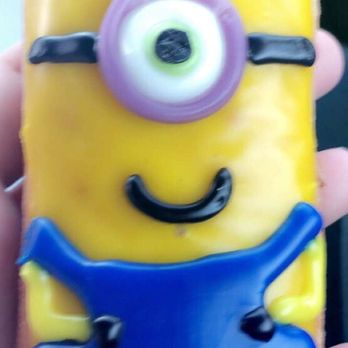 Kim's Donuts - a hand holding a donut decorated like a minion - Donuts Near Me - Tulsa, Oklahoma