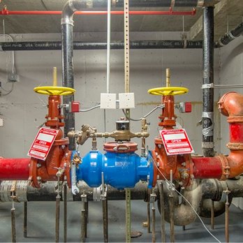 Spartan Fire Protection - A mechanical room features red and black pipes with yellow valves and red warning tags. Center is a blue valve assembly... - Fire Protection Services Near Me - Houston, Texas Spartan Fire Protection - A mechanical room features red and black pipes with yellow valves and red warning tags. Center is a blue valve assembly... - Fire Protection Services Near Me - Houston, Texas