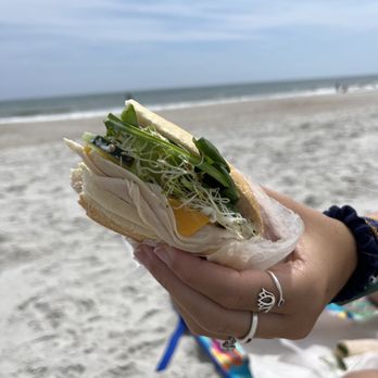 Sub Cultured - a person holding a sandwich on the beach - Salad Near Me - Atlantic Beach, Florida