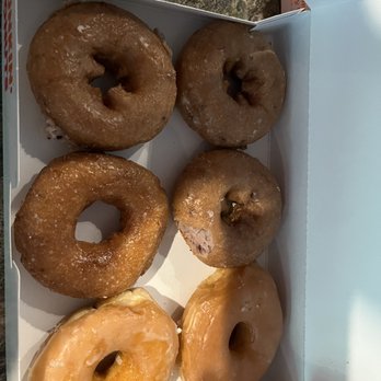 Dunkin' -  six glazed donuts in a box - A white box contains six donuts with different flavors and toppings. The donuts include glazed, chocolate-covered, and plain varieties, arranged in two rows. The box is open, revealing the assortment of donuts, which are placed on a textured surface. The donuts vary in appearance, with some having a shiny glaze and others a matte finish, indicating different flavors and toppings. - Donuts Near Me - Geneva, Ohio