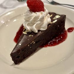 Cannova's Pizza - From the 2023 holiday musical show special menu: Course 5 -- flourless chocolate cake with gold fleck, whipped cream, and raspberry coulee