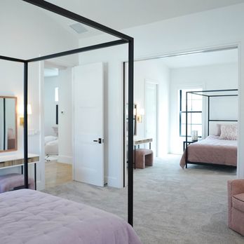 Millenia Luxury Homes - View into two bedrooms connected by a shared space, both featuring black canopy beds and pink accent chairs, in a Gilbert, Arizona home. - General Contractors Near Me - Mesa, Arizona Millenia Luxury Homes - View into two bedrooms connected by a shared space, both featuring black canopy beds and pink accent chairs, in a Gilbert, Arizona home. - General Contractors Near Me - Mesa, Arizona