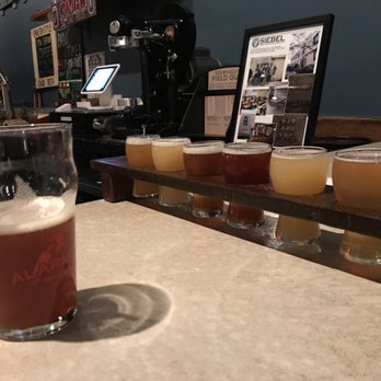 Alarmist Brewing & Taproom - A pint of the cask Blunderbuss with cranberry, pecans, and Rosemary on the left, and a flight for my IPA-loving son on the right. - Breweries Near Me - Chicago, Illinois