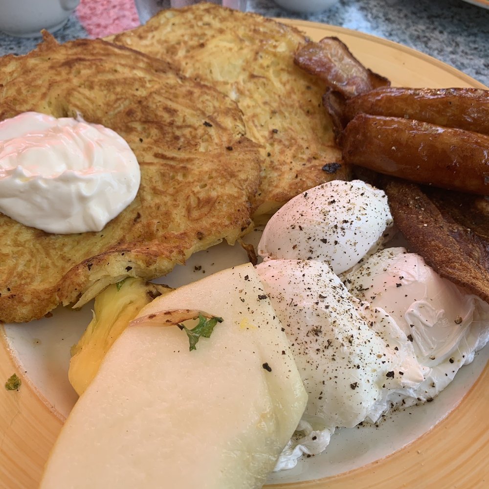 Potato pancakes with poached eggs, bacon, sausage and a side of fruit. Potato pancakes with poached eggs, bacon, sausage and a side of fruit.