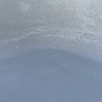 Burkett’s Pool Plastering - Dent in the plaster by Burkett employee. - The image depicts a close-up view of a smooth, light-colored surface, possibly a pool's plaster or finish. A noticeable dent or indentation is present, along with some scratches and surface imperfections. The surface appears clean but shows signs of damage or impact, relevant to pool maintenance or repair context. - Pool & Hot Tub Service Near Me - Ripon, California