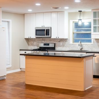 M & H Construction - a kitchen with white cabinets and wood floors - General Contractors Near Me