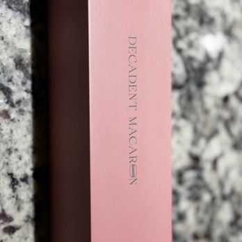 Decadent Macaron - A pink rectangular box with the words "Decadent Macarons" printed on the side, placed on a speckled granite surface. - Macarons Near Me - Gilbert, Arizona