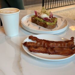 Necessary Purveyor - Poached egg and avocado on toast. Bacon on the side and coffee.