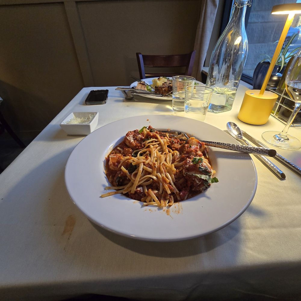 Toscano Bistro - Background - pork chop with apple and roasted Brussel sprouts.  Foreground - shrimp and scallop Fra Diavolo with linguine. - Italian Near Me - Williston, Vermont
