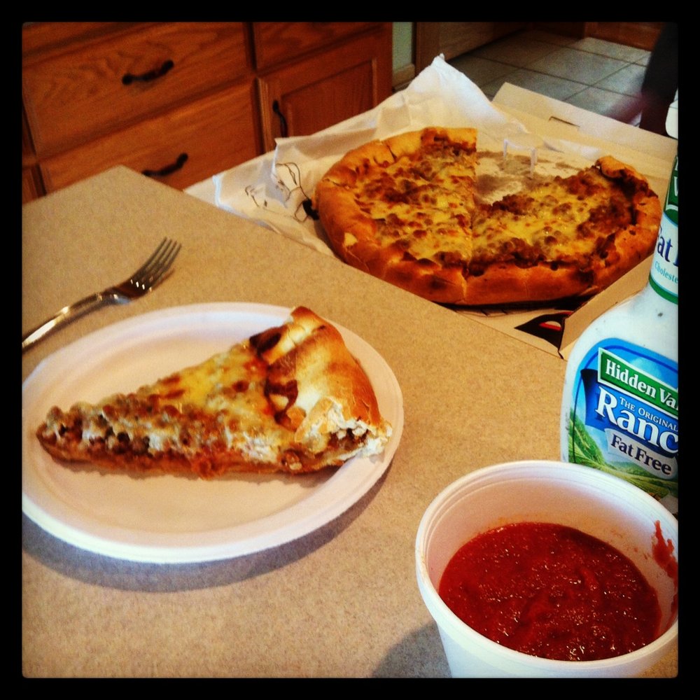 a slice of pizza on a plate next to a bowl of ketchup