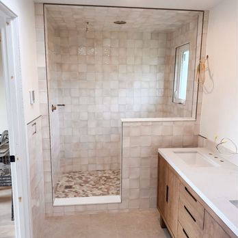Dm Construction Group - Warm-toned bathroom remodel in Ballard featuring handmade-look tile, pebble shower floor, and natural wood vanity. By DM Construction Group. - General Contractors Near Me - Maple Valley, Washington