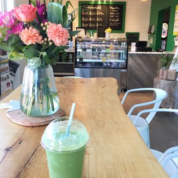 Glow Juicery - a green smoothie and a vase of flowers - Juice Bars & Smoothies Near Me - Hamilton, Ontario