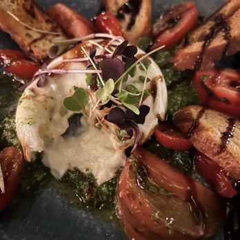 Rooftop - Heirloom Tomato & Burrata | heirloom tomatoes, arugula pesto, burrata cheese, toasted crostinis - A dish featuring heirloom tomatoes, burrata cheese, toasted crostinis, and microgreens, served on a dark plate with balsamic glaze. - New American Near Me - Walnut Creek, California