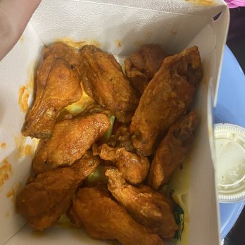 ATL Wings - Medium - Fried chicken wings coated in sauce are inside a takeout box, with a small container of dipping sauce nearby. - Chicken Wings Near Me - Mesa, Arizona