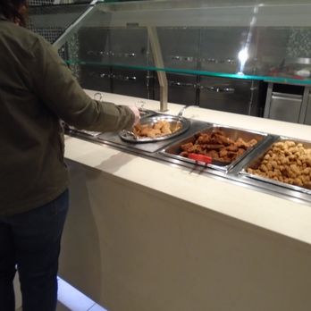 Tradewinds Buffet - A person in a brown jacket is serving fried chicken from a buffet at Tradewinds Buffet, which offers a variety of seafood and classic dishes. - Buffets Near Me - Welch, Minnesota