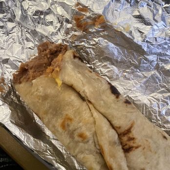 La Tejana - A breakfast burrito with visible meat and egg filling, wrapped in a flour tortilla, partially eaten and placed on aluminum foil. - Tex-Mex Near Me - Washington, DC, District of Columbia