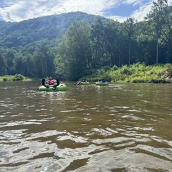 Green River Adventures - People in tubes in a river surrounded by mountains.