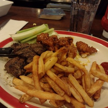 99 Restaurants - a plate of food on a table - A plate with French fries, celery sticks, and fried chicken pieces is on a restaurant table, with a glass of water and a deck of cards in the background. - American Near Me - Concord, New Hampshire