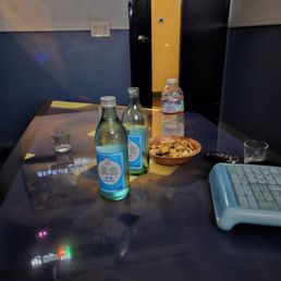 a table with a keyboard, a bottle of water, and a bowl of chips