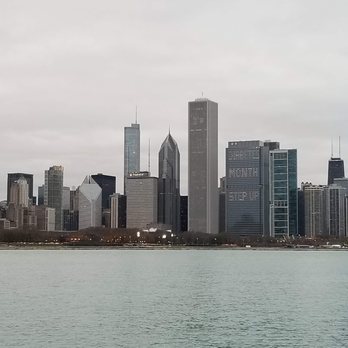 Chicago Skyline - A city skyline with numerous high-rise buildings is seen across Lake Michigan on a cloudy day. - Local Flavor Near Me - Chicago, Illinois