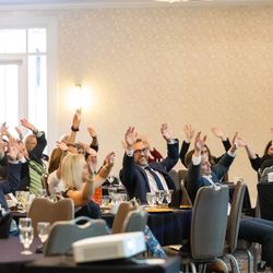 Omega Senior Living - Team members enjoying a roller coaster activity at the Leadership Conference Gala--hands up for fun and engagement, inspired by the keynote!