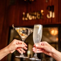 Lounge 31 - Hands toasting with martini and champagne at Lounge 31's bar with warm ambient lighting.