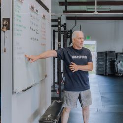 Transform Fitness - "A coach leads the class solo at the whiteboard, explaining the workout while members listen."