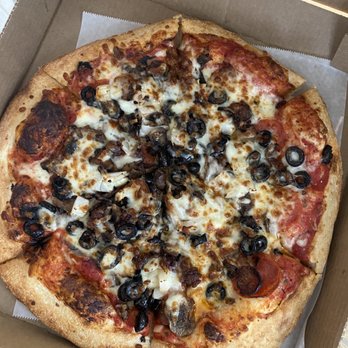 Davidos - 12" Deluxe pizza - A 12-inch pizza with a golden-brown crust, topped with melted cheese, sliced black olives, mushrooms, and meat toppings, presented in a cardboard pizza box with parchment paper lining the bottom. - Pizza Near Me - Rio Rancho, New Mexico